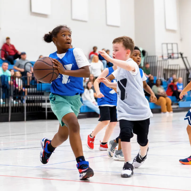 A group of youth basketball players play a game inside a gym.
