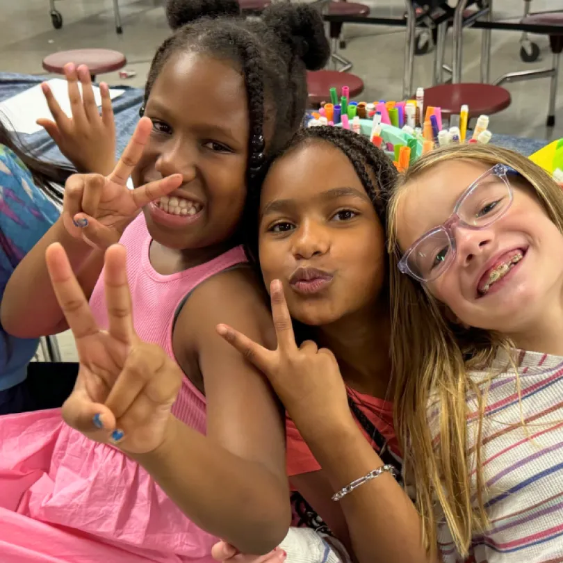 Three girls smile together in the YMCA afterschool program.