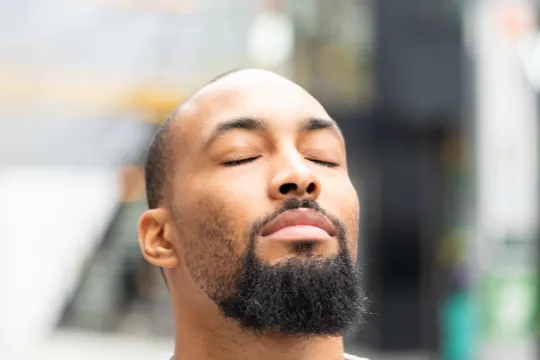 A man closes his eyes as he takes a moment of calm time.