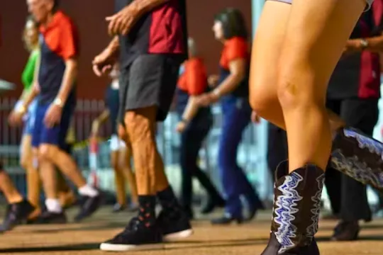 A close up of people dancing in a line dancing class.