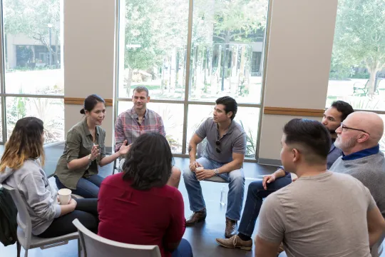 A support group meets inside and engages in conversation.