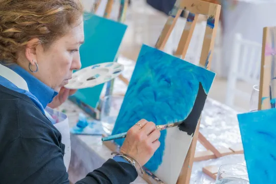 A group of people paint a winter scene during an art class.