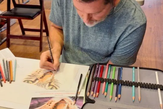 A man uses color pencils during a group art class.