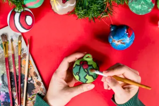 A person paints a holiday-themed ornament.