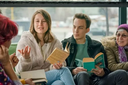 A diverse group of people enjoy a discussion during their book club.