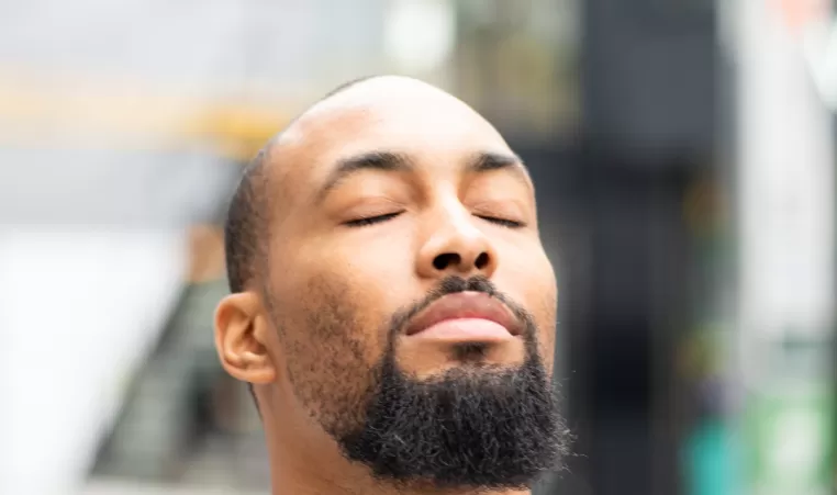 A man closes his eyes as he takes a moment of calm time.