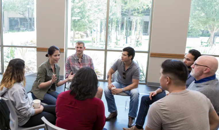A support group meets inside and engages in conversation.