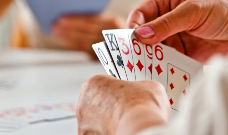 A close-up of someone holding cards during a bridge game.
