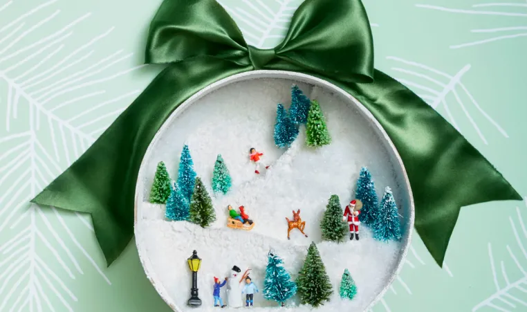 A winter diorama craft made with the lid of a mason jar.