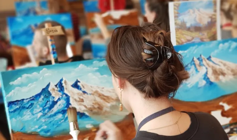 People participate in a Bob Ross painting class.